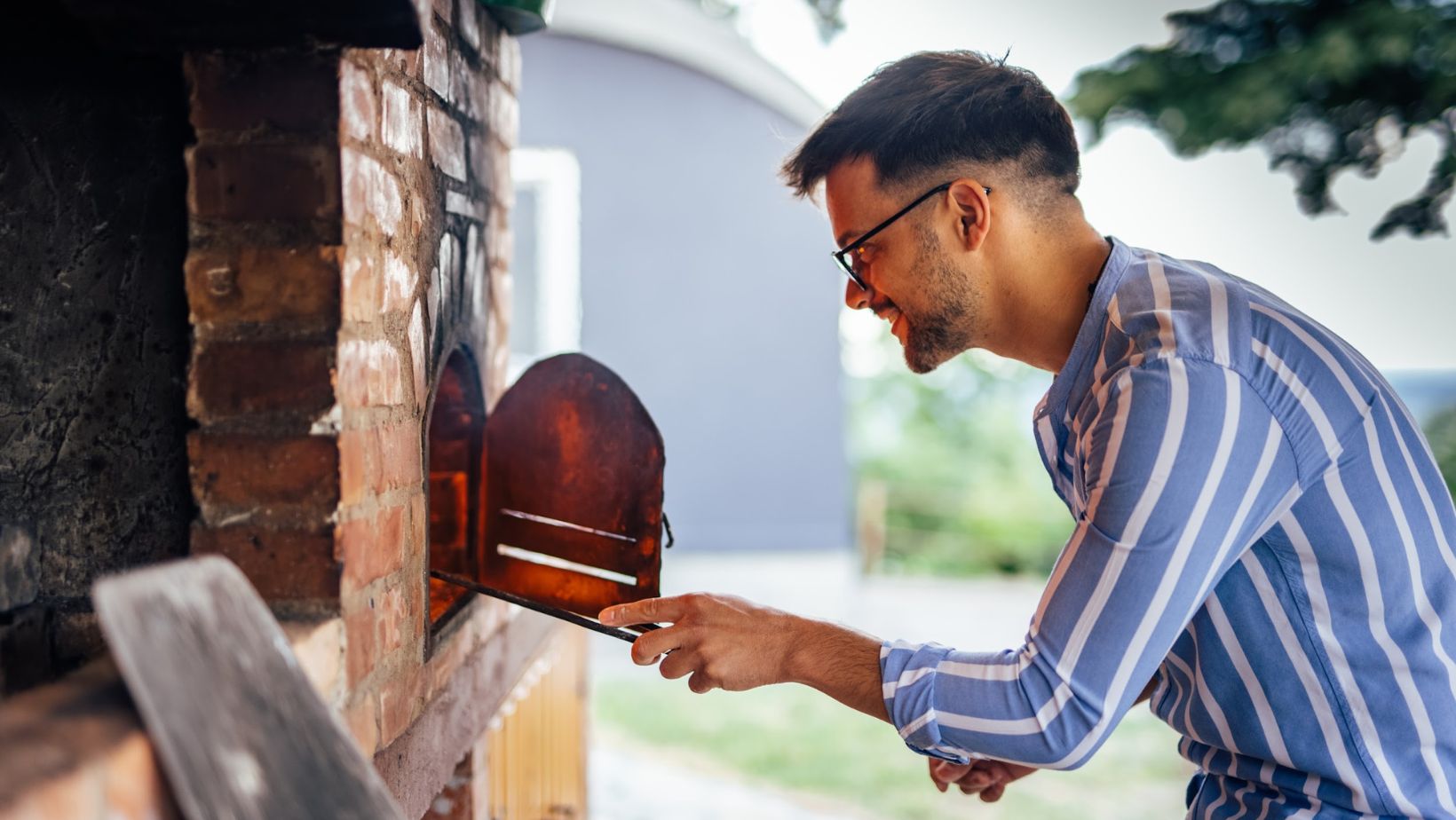 A man adding wood into the oven