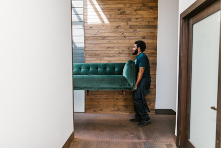 Men holding up a green couch